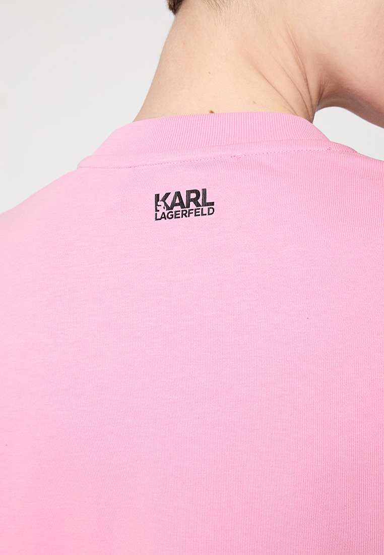 Rosa Baumwoll-T-Shirt mit Rundhalsausschnitt und einem kleinen schwarzen "KARL LAGERFELD" Logo, das zentral hinten am Kragen platziert ist.