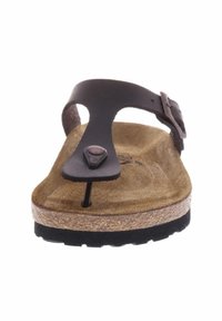 Bruine leren sandaal met een teenlus, kurken voetbed en zwarte rubberen zool. Voorzien van een metalen gesp en een gestructureerd oppervlak van het voetbed.