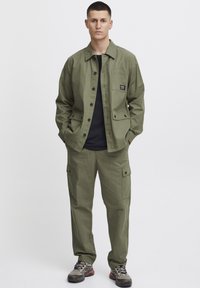 Olijfgroene jacket met een borstzak, knoopsluitingen, gecombineerd met bijpassende cargobroek met zijzakken en een ontspannen pasvorm.