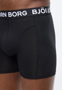 Μαύρα ανδρικά μποξέρ με ορατές ραφές και φαρδιά μέση που φέρει το όνομα της μάρκας "BJÖRN BORG" με λευκά γράμματα.