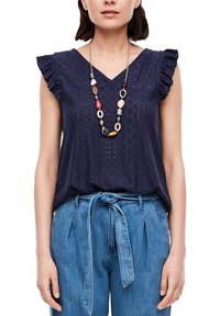 Haut sans manches bleu marine avec un col en V, épaules à volants, motif en broderie anglaise texturée. Associé à un pantalon taille haute bleu clair avec ceinture.