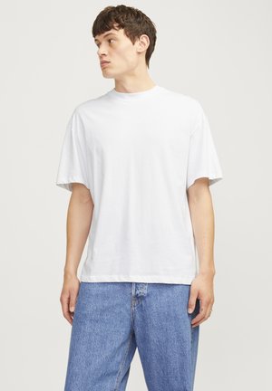 Hvid bomulds T-shirt med en afslappet pasform, korte ærmer og rund hals, parret med blå denimjeans. Glat tekstur, minimalistisk design.