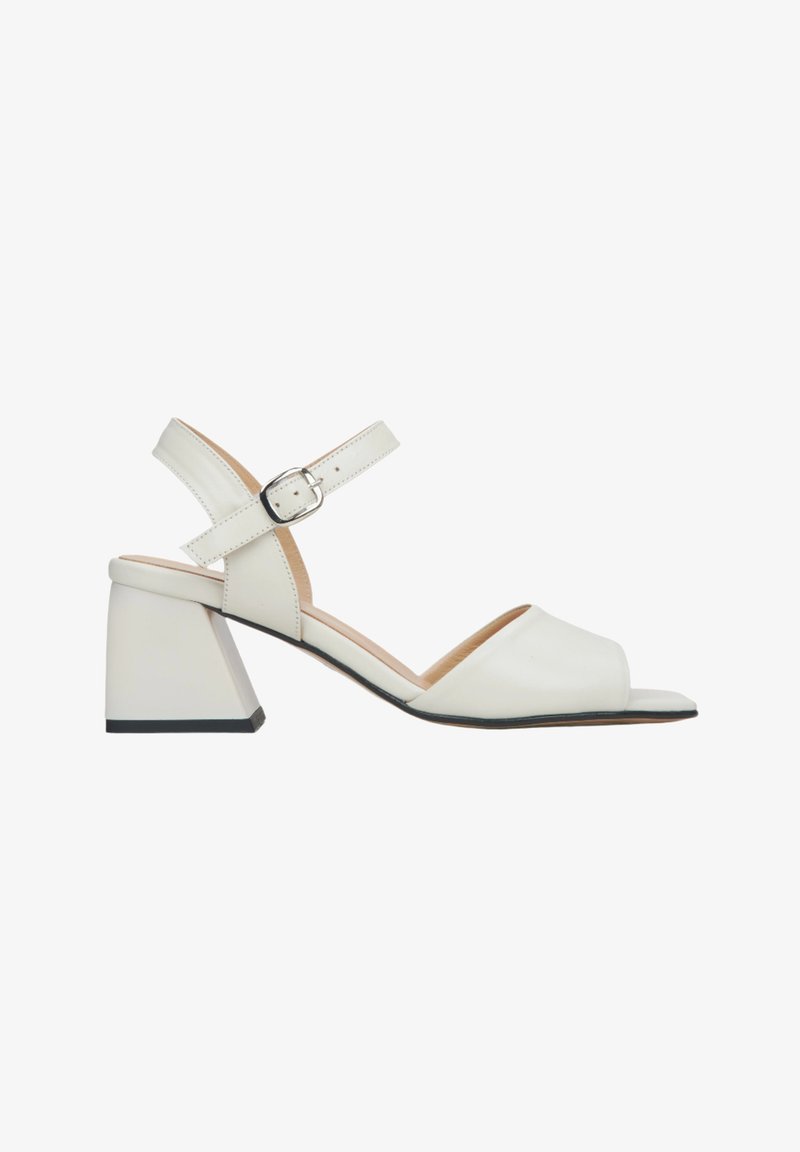 Białe skórzane sandały na blokowym obcasie, z odkrytą palcą, regulowanym paskiem na kostce i minimalistycznym designem. Akcenty na czarnej podeszwie.