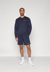 Ensemble en coton bleu marine composé d'un sweatshirt et d'un short avec logos. Le sweatshirt présente un col rond, des poignets en côte et une coupe décontractée.