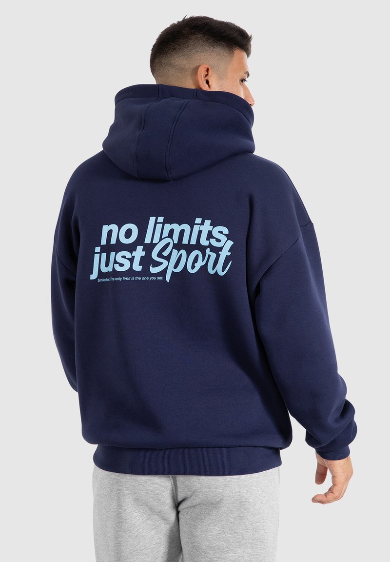 Sweat à capuche bleu marine avec un grand texte bleu clair au dos portant la mention "sans limites juste du sport". Doté d'une capuche spacieuse et de poignets côtelés.