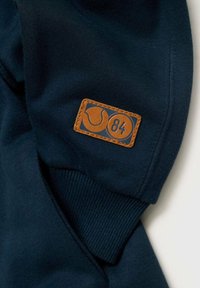 Marineblauwe sweatshirt met een gestructureerde afwerking, voorzien van een rechthoekige, bruine leren patch met een logo en het nummer "84."