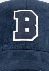 Marineblaue Wildleder-Cap mit einem großen, weiß umrandeten, marineblauen Buchstaben "B", der auf das Vorderpanel gestickt ist.