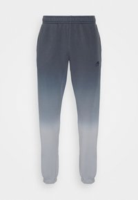 Pantaloni della tuta grigi con effetto ombre, che passano da un grigio scuro nella parte superiore a un grigio chiaro nella parte inferiore. Presentano una vita elastica e polsini.