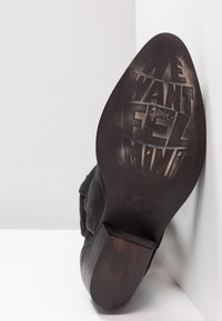 Podeszwa czarnego skórzanego buta na słupku z wytłoczonym napisem "CHCEMY FEL MINT" oraz rozmiarem 37.