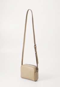 Borsa a tracolla in pelle beige con forma rettangolare, tracolla regolabile, chiusura con zip e dettagli in rilievo minimalisti sulla parte frontale.