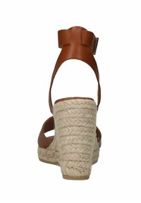 Braune Leder-espadrilles mit einem geflochtenen Juteabsatz, ausgestattet mit einem Fesselriemen und einem dekorativen Schleifenakzent am Knöchel.