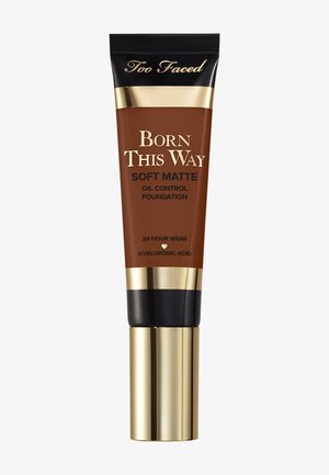 Tube de fond de teint Too Faced Born This Way Soft Matte à contrôle d'huile avec bouchon doré et noir, tenue 24 heures, et acide hyaluronique mentionné.
