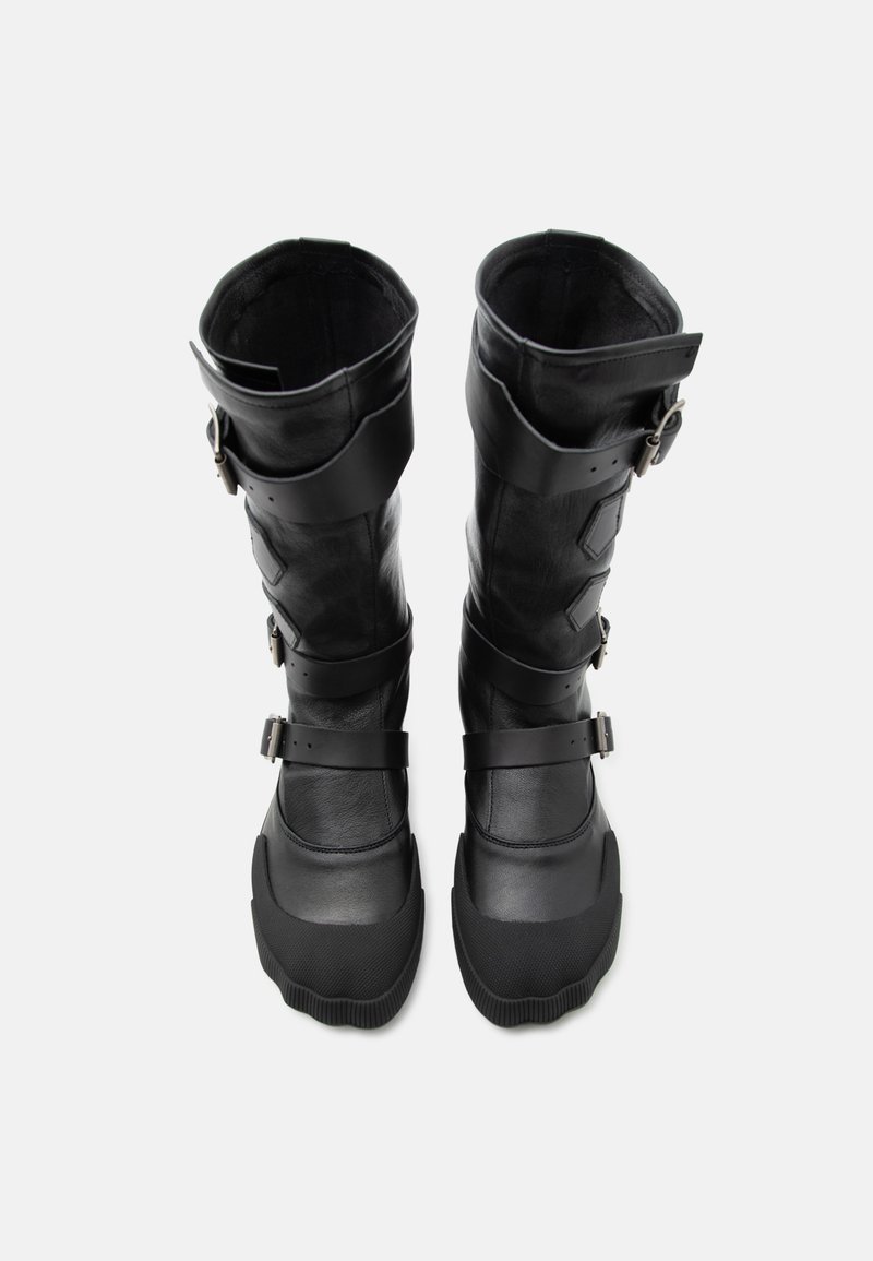 Stivali alti in pelle nera con molteplici fibbie regolabili e puntali rinforzati, mostrati in verticale su sfondo bianco.