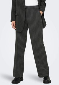 Pantaloni grigi a righe con design a gamba dritta, caratterizzati da una vita alta e una sottile texture, abbinati a stivali neri chunky.