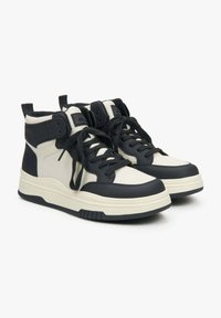 Wysokie sneakersy w czarnej i kremowej skórze. Wśród cech znajdują się czarne sznurówki, wyściółka w okolicy kostki oraz fakturowana kremowa podeszwa.