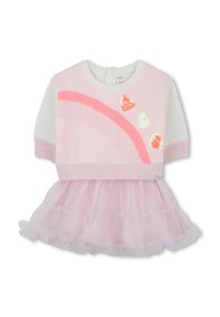 Top en tricot rose et blanc avec un design arc-en-ciel et des cœurs en sequins, associé à une jupe en tulle rose superposée. Tissus doux et texturés.