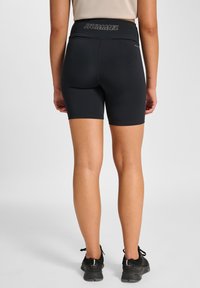 Svarta sportshorts med hög midjeresår och en "HUMMEL"-logga. Tillverkade av ett slätt, stretchigt tyg, designade för komfort och rörelse.