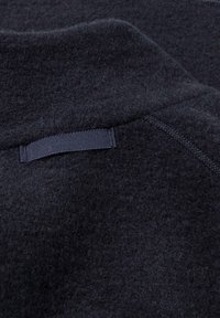 Dunkler Wollpullover mit strukturierter Oberfläche und sichtbaren Nähten. Verfügt über einen kurzen Rippkragen und eine angenähte Stoffschlaufe auf der Rückseite.