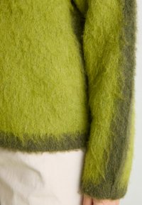 Πλεχτό πουλόβερ σε φωτεινό και σκούρο πράσινο χρώμα, με χνουδωτή υφή και σχέδιο χρώματος σε συμπαγές μπλοκ στο τελείωμα και τα μανίκια.