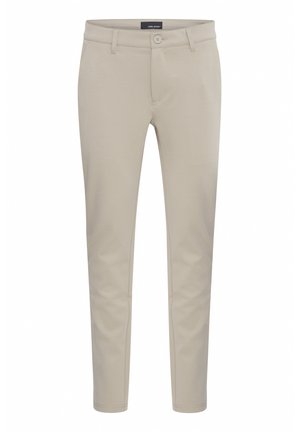 Pantaloni beige su misura con zip e chiusura con bottone. Presentano tasche anteriori, vestibilità slim e una texture liscia e opaca.