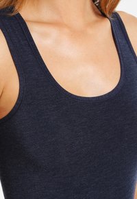 Marineblauwe tanktop met een ronde hals, gemaakt van zachte, rekbare stof. Heeft een gladde textuur en een getailleerd ontwerp.