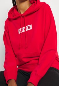 Sudadera roja de mezcla de algodón, con un gran logo blanco de Levi's en el pecho, de corte relajado y capucha con cordón.