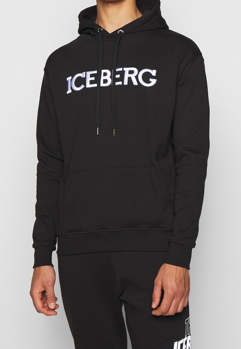 Sudadera negra con "ICEBERG" bordado en blanco, con un bolsillo frontal, cordones ajustables y puños y dobladillo acanalados.