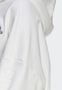 Sudadera blanca con capucha, que presenta un tejido texturizado, un corte oversize y el logotipo bordado de adidas en la manga. Material suave con diseño con capucha.