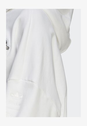 Bílá mikina s kapucí vyrobená z texturované látky, oversized střih a vyšívané logo adidas na rukávu. Měkký materiál s designem s kapucí.