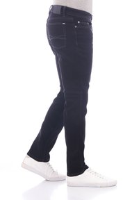 Pantalones vaqueros de denim negro con un corte ajustado, que cuentan con costuras blancas, un diseño clásico de cinco bolsillos y una textura suave.