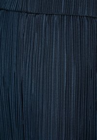 Plooide donkerblauwe stof met verticale ribbels, zichtbaar met een gladde textuur en subtiele glans, geschikt voor kleding of bekleding.