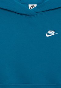Turkio spalvos Nike tamprinė su balta logotipu, su kengūros kišene ir tekstūruota medžiaga. Apačia ir rankogaliai turi raukšlių apdailą.