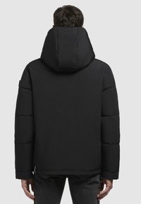 Sort pufferjakke med høj krave og hætte, udstyret med en quiltet design, tekstureret stof og en lige kant.
