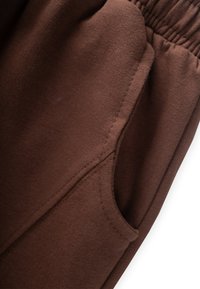 Rudos sportiniai kelnės, pasižyminčios minkšta tekstūra, elastingu juosmeniu ir šonine kišenę su matomu siūlų dekoru.