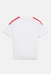 Άσπρο πουκάμισο με κοντά μανίκια και κόκκινες ρίγες ως λεπτομέρειες στους ώμους, κατασκευασμένο από λείο ύφασμα. Διαθέτει στρογγυλή λαιμόκοψη και μανίκια ράγκλαν.