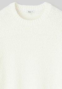 Pull en tricot blanc ample avec un col rond. Motif texturé sur l'ensemble, avec un col côtelé et une étiquette à l'intérieur indiquant la taille L.