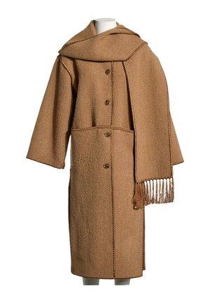 Manteau en laine marron avec de gros boutons et une écharpe à franges assortie drapée sur une épaule d'un mannequin.