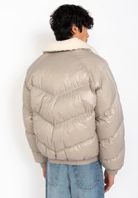 Beige pufferjack met een schapenvacht kraag, met een textuurafwerking en zigzagpatroon, elastische manchetten en een cropped ontwerp.