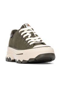 Zapatillas de lona verde oliva con cordones blancos y suelas de goma, que presentan una suela externa gruesa y texturizada, así como un pequeño parche de logo en la lengüeta.