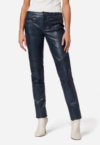 Navy leren broek met een slim fit, voorzien van ribbeldetails op de knieën en discrete zijzakken. Soepele textuur met een subtiele glans.