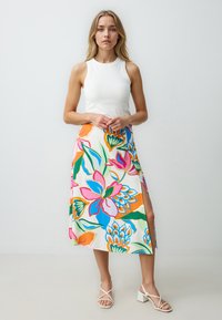 Bloemen midi rok met felle roze, blauwe en groene patronen. Gemaakt van lichtgewicht stof, met een zijsplit en levendige kleurcontrasten.