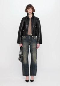 Svart läderjacka med en kort design, parat med blekta blå raka jeans. Accessoarer inkluderar en liten svart handväska och spetsiga klackar.