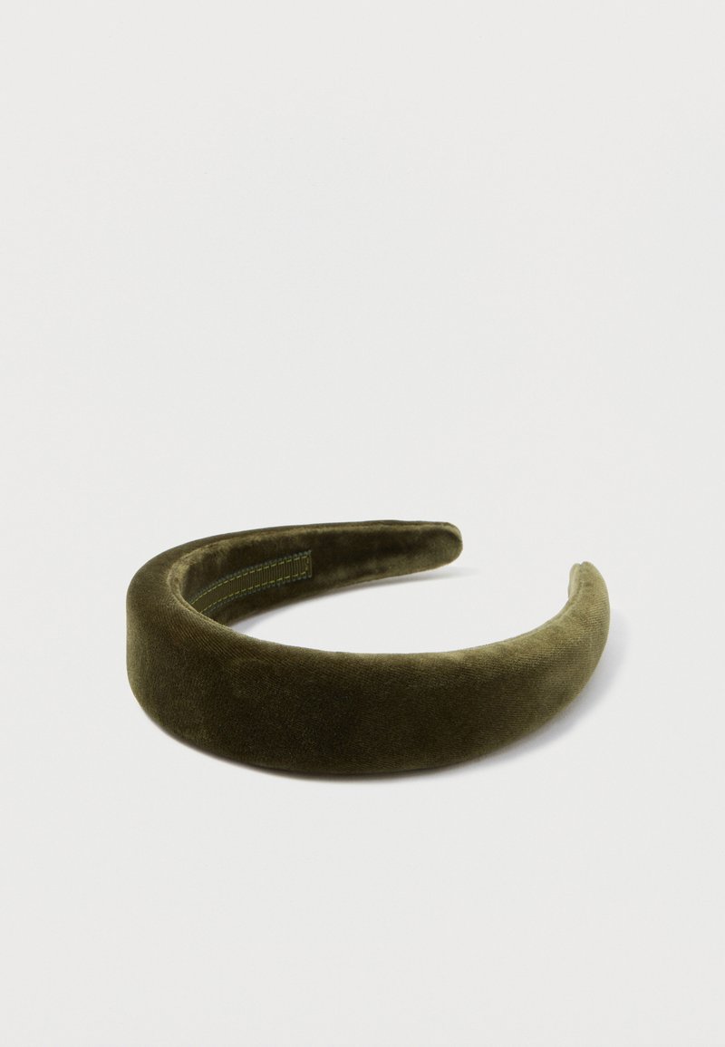 Diadema de terciopelo en verde oliva oscuro. Textura suave con un acabado liso. Forma redondeada con una ligera curva y detalles cosidos en el lado interior.