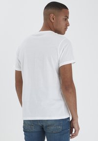 T-shirt bianco in cotone con maniche corte, collo rotondo e colletto a costine in contrasto. Presenta una vestibilità comoda e una texture liscia e leggera.