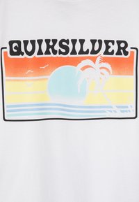 Balta marškinėliai su spalvinga grafika, ant kurios yra žodis "Quiksilver." Dizainas apima saulėlydžio gradientą, palmės siluetą ir bangas.