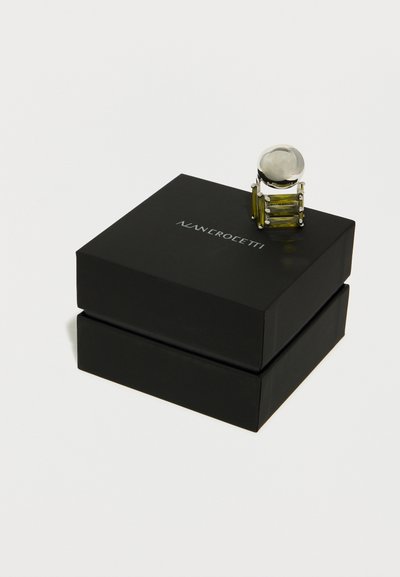 Ασημένιο και πράσινο ορθογώνιο δαχτυλίδι με πολύτιμη πέτρα, τοποθετημένο σε κλειστό μαύρο κουτί με την επωνυμία "Alan Crocetti".