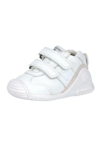 Zapatillas blancas para niños con dos correas de Velcro ajustables, suela de goma texturizada y un acento gris en el costado con un logo de la marca.
