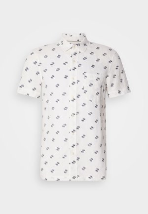 Lyhythihainen, valkoinen pellavapaita, jossa on hienovarainen laivastonsininen kuvio, napillinen kaulus ja yksi rintatasku. Rakenteellinen, hengittävä kangas.