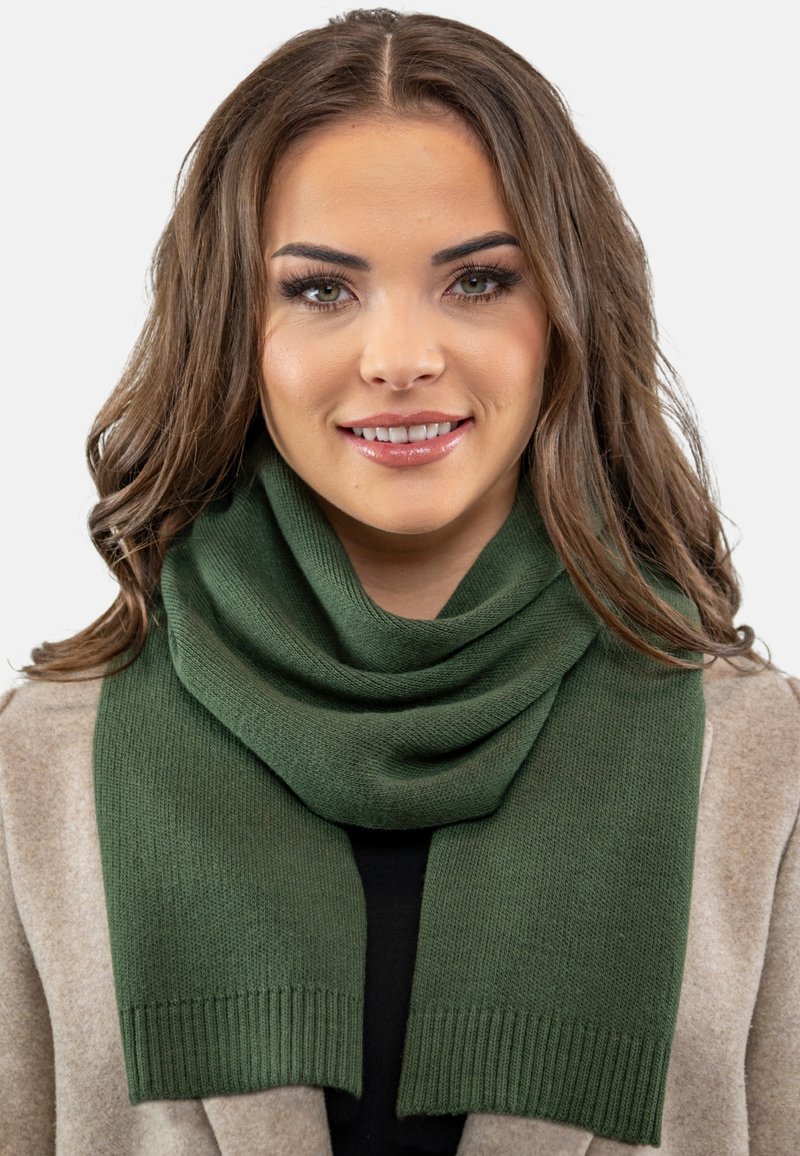 Fular de culoare verde închis, realizat dintr-un material moale, cu margine ribelată și stil drapat, purtat peste un palton bej deschis.