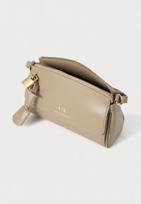 Beige leather handbag with a smooth texture, gold zipper, and logo detail. Features a front pocket and a removable lock accessory.